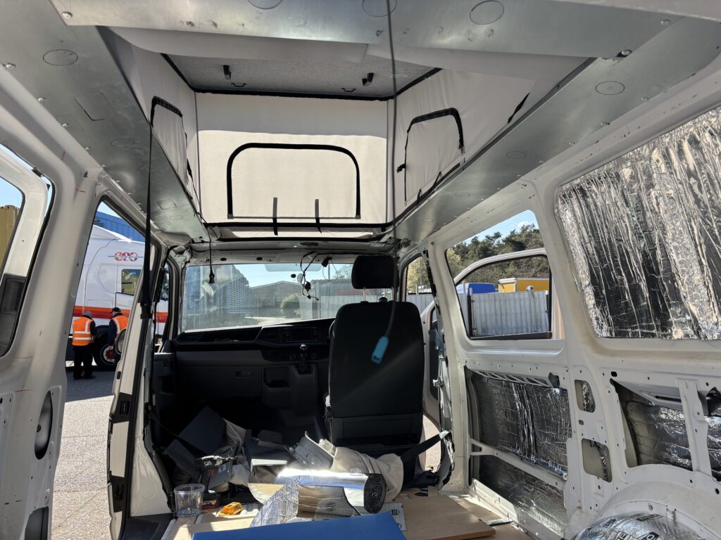 Campervan conversion in progress with pop-top canvas fitted and foil wall insulation