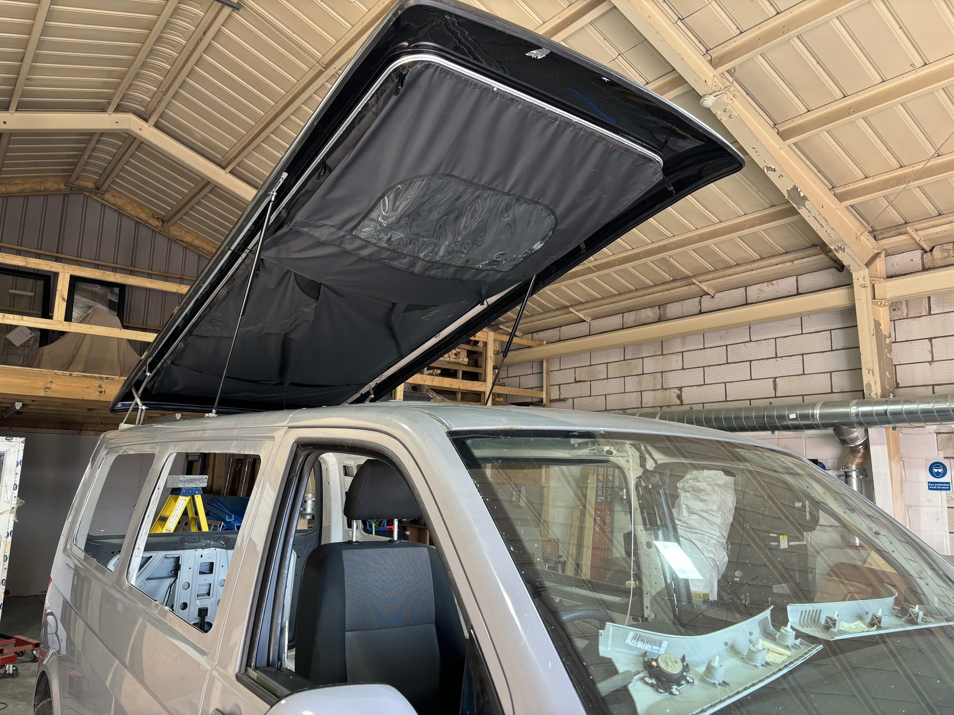 Raised pop-top roof with canvas sides fitted to a campervan in the workshop
