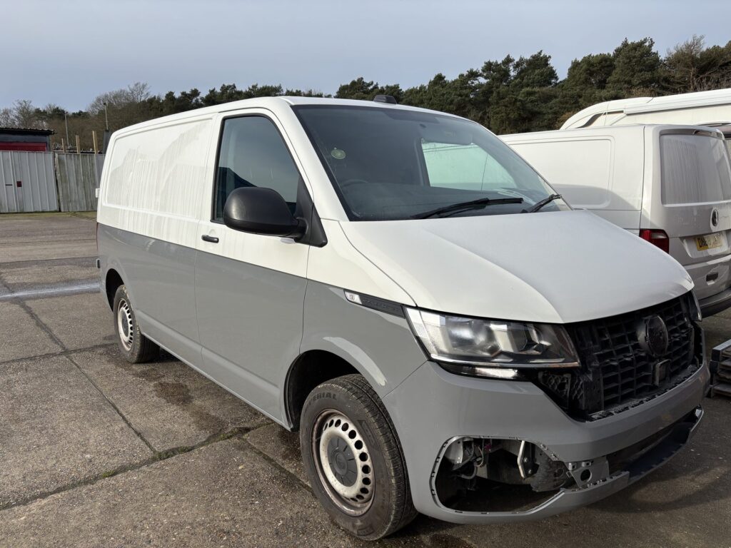 Two-tone white and grey VW Transporter van parked in a yard before conversion